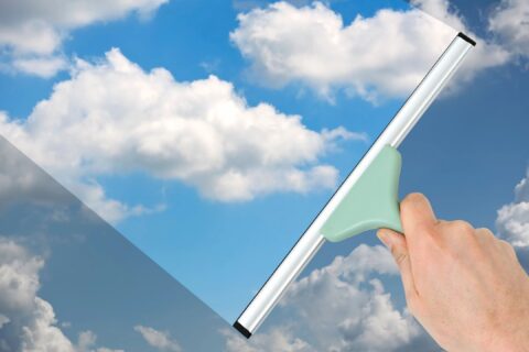 Image of White Squeegee cleaning Window with clouds and sky reflection